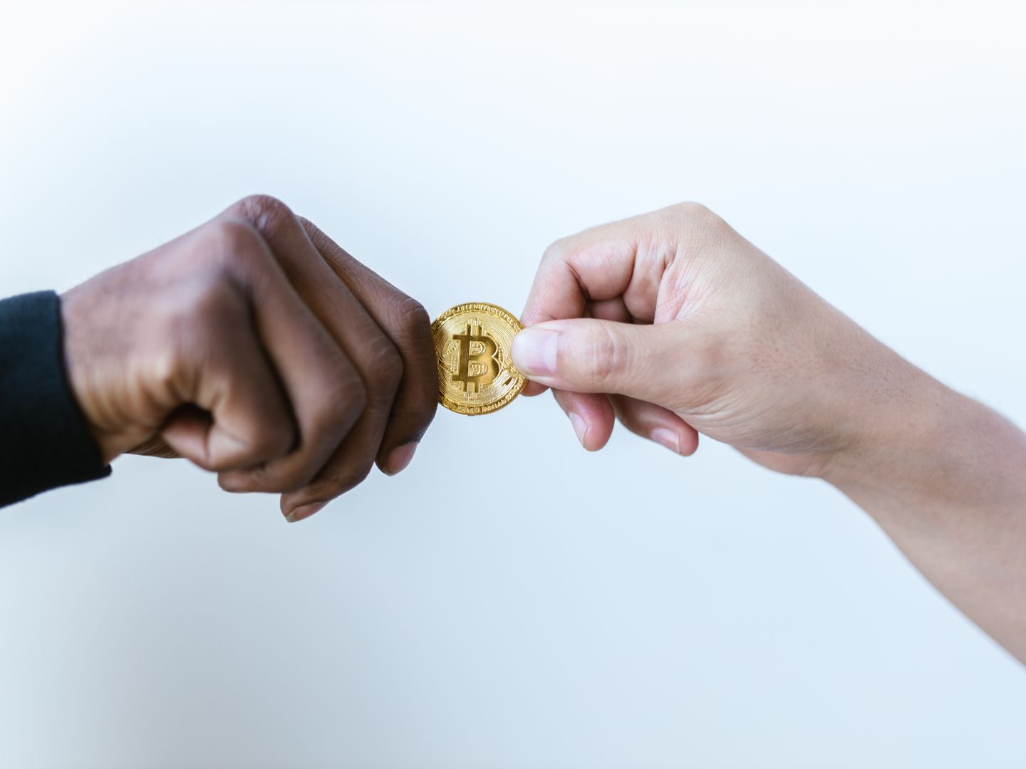 Two hands exchanging a Bitcoin coin, symbolizing cryptocurrency transactions.