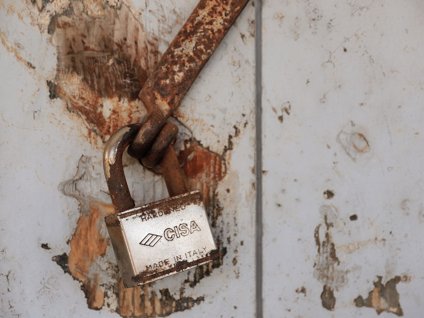 Detailed shot of a rusty padlock on a weathered door conveying security and time passage.