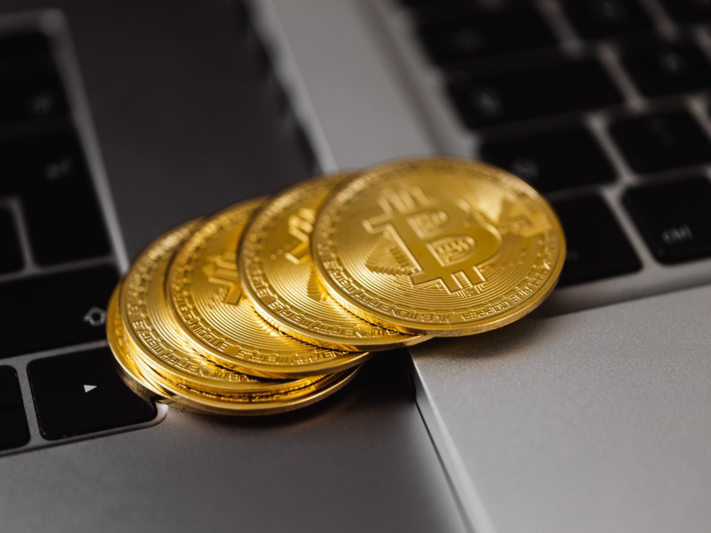 Close up of golden bitcoins on a laptop keyboard representing digital currency and wealth.